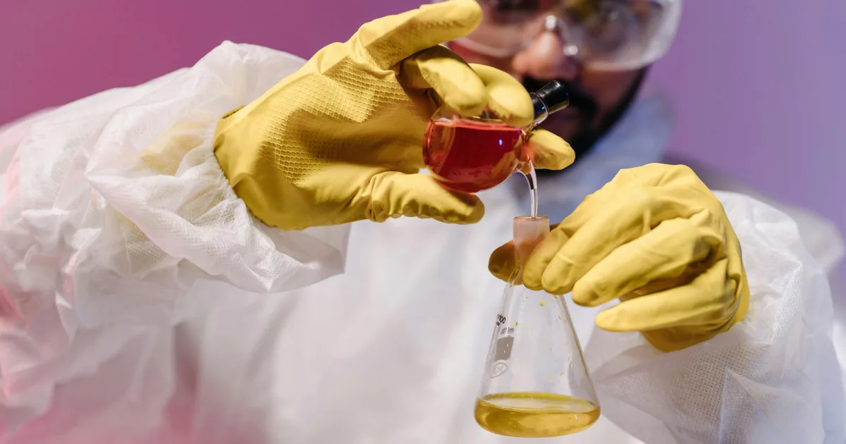 An image of a chemist/lab technician working with a chemical formula which will ultimately become fragrance/parfum petrochemicals.